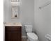 Neutral toned powder room featuring tile flooring, vanity with mirror, and elongated toilet at 9899 Leland Dr, Orlando, FL 32827