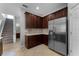 View of kitchen with stainless steel refrigerator, dark wood cabinetry, stairs and hallway at 9899 Leland Dr, Orlando, FL 32827