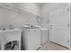Bright laundry room featuring a utility sink, washer and dryer, wire shelving and white door at 9899 Leland Dr, Orlando, FL 32827