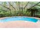 Sparkling pool surrounded by brick patio and lush trees within screened enclosure at 9899 Leland Dr, Orlando, FL 32827