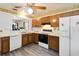 Traditional kitchen with wood cabinets, white appliances, and a window looking into the living space at 1148 Monroe Ave, St Cloud, FL 34769