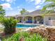 A gorgeous view of the rear exterior with a covered patio, swimming pool, and lush landscaping at 116 Cherry Creek Cir, Winter Springs, FL 32708