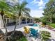 Lush backyard showcasing a pool, patio, colorful Adirondack chairs and manicured landscaping at 116 Cherry Creek Cir, Winter Springs, FL 32708