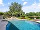 Stunning freeform pool with rock waterfall feature surrounded by lush landscaping and serene lake views at 116 Cherry Creek Cir, Winter Springs, FL 32708