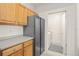 Kitchen area with wooden cabinets and stainless steel refrigerator leading to laundry room at 12016 Villanova Dr # 101, Orlando, FL 32837