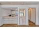 Pass-through view of kitchen with bright countertops and white cabinets, and connection to the living room at 1236 Villa Ln # 143, Apopka, FL 32712