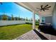 A covered patio with a ceiling fan and a grill overlooks a well-manicured backyard with a pristine privacy fence at 13301 Mcmillan Dr, Orlando, FL 32827