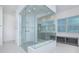 Sleek bathroom with a glass shower enclosure, gray cabinets, a built-in bench, and neutral tile flooring at 13307 Alderley Dr, Orlando, FL 32832