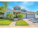 Inviting two-story home with stone accents, a charming balcony, three-car garage, and a beautifully landscaped front yard at 13307 Alderley Dr, Orlando, FL 32832