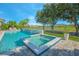 Backyard pool and spa area with a waterfall feature and views of the golf course and neighboring homes at 13307 Alderley Dr, Orlando, FL 32832
