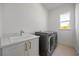 Well-lit laundry room featuring modern washer and dryer and a sink under the window at 15060 Brodie Ln, Winter Garden, FL 34787