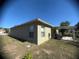 A green backyard with a small patio, outdoor seating, and bright blue sky at 1956 Myakka Ct, Poinciana, FL 34759