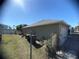 Backyard featuring partial fence, green lawn, and the side of the beige single Gathering home at 1956 Myakka Ct, Poinciana, FL 34759