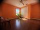 Bright bedroom with wood floor, large window with plants, and orange walls at 1956 Myakka Ct, Poinciana, FL 34759