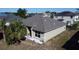 Rear exterior view showing a well-kept home with a gray roof, manicured landscaping, and a large palm tree at 1956 Myakka Ct, Poinciana, FL 34759