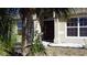 Inviting front entrance with a dark wooden door, manicured landscaping, white rock accents, and a healthy palm tree at 1956 Myakka Ct, Poinciana, FL 34759