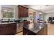 A modern kitchen with stainless steel appliances, dark countertops, and cherry wood cabinets offers a view to the outdoor pool at 2629 Maggiore Cir, Kissimmee, FL 34746