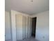 Neutral bedroom featuring bi-fold closet doors and an open doorway to other areas of the home at 30162 Rustic Mill St, Mount Dora, FL 32757