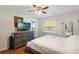 Cozy bedroom featuring light walls, a ceiling fan, wood floors, and a dresser with a modern television at 311 E Wallace St, Orlando, FL 32809