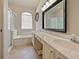 Well-lit bathroom features a double vanity, large mirror, and a shower-tub combo with sliding glass door at 405 Carriage Way Ct, Oviedo, FL 32765