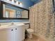 Stylish blue bathroom featuring a classic vanity, a large mirror, and a shower-tub combo with floral curtain at 405 Carriage Way Ct, Oviedo, FL 32765