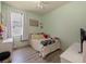 Bright bedroom features a neutral ceiling fan, light green walls, a window, and wood-look floors at 405 Carriage Way Ct, Oviedo, FL 32765