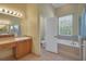 Well-lit bathroom with a soaking tub, glass enclosed shower, and vanity with ample counter space at 4536 Barrister Dr, Clermont, FL 34711