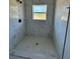White tiled shower with black fixtures and patterned shower floor, illuminated by a sunlit window at 4537 Conley St, Orlando, FL 32811