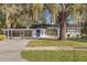Charming single-story home featuring a blue front door, lush landscaping, and beautiful trees draped in Spanish moss at 719 Se 24Th St, Ocala, FL 34471
