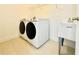 Well-lit laundry room featuring a side-by-side washer and dryer, white utility sink, and modern tile flooring at 827 Dennis Ave, Orlando, FL 32807