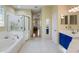 Bright bathroom featuring a soaking tub with shower, updated vanity, and toilet with a view to bedroom at 8912 Heritage Bay Cir, Orlando, FL 32836