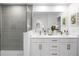 Stylish bathroom featuring double sinks, a large mirror, and a tiled shower with glass door at 1287 Tarflower Dr, Winter Springs, FL 32708