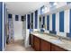 Modern bathroom with blue stripes, double sinks, and a well-lit shower, for a refreshing experience at 1304 Independence Ln, Mount Dora, FL 32757