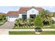 Charming home featuring a terracotta roof, lush tropical landscaping, and a brick-paved driveway and walkway at 13349 Alderley Dr, Orlando, FL 32832
