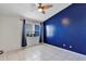 Bedroom featuring blue accent wall, neutral tile flooring, and a ceiling fan for comfort at 2568 Woodgate Blvd # 204, Orlando, FL 32822