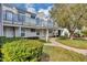 Two-story condo with sidewalk and blue railings, complemented by lush landscaping and a large shade tree at 2568 Woodgate Blvd # 204, Orlando, FL 32822