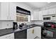 White kitchen featuring black countertops, appliances, ample cabinetry, and a window for natural light at 2568 Woodgate Blvd # 204, Orlando, FL 32822