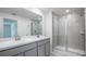 Bathroom with double sink vanity, a large mirror, and a tiled glass door shower at 307 Corsica Ct, Kissimmee, FL 34758
