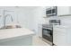Bright kitchen featuring stainless steel appliances, white cabinetry, and a large sink with elegant faucet at 307 Corsica Ct, Kissimmee, FL 34758