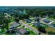 A suburban aerial view reveals a light blue home amidst lush green lawns and mature trees in a well-planned neighborhood at 311 W Delaware Ave, Lake Helen, FL 32744
