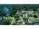 A suburban aerial view reveals a light blue home amidst lush green lawns and mature trees in a well-planned neighborhood at 311 W Delaware Ave, Lake Helen, FL 32744