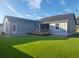 A view of the home's backyard and back exterior, complete with a deck and green lawn at 311 W Delaware Ave, Lake Helen, FL 32744