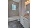 Cozy bathroom featuring a tiled shower-tub, white vanity, and gray flooring at 311 W Delaware Ave, Lake Helen, FL 32744