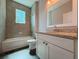 Bathroom featuring gray tiled walls, granite vanity, and combined bath and shower for a spa-like experience at 311 W Delaware Ave, Lake Helen, FL 32744