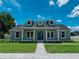 Inviting home boasts a blue double-door entry, dormer windows, a lush lawn, and a quaint front porch at 311 W Delaware Ave, Lake Helen, FL 32744