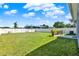 Expansive backyard with a green lawn, defined by a crisp white fence, and patio furniture at 312 Inman Blvd, Winter Haven, FL 33881