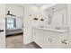 Modern bathroom with double vanity, white cabinets, and view to bedroom with ceiling fan at 312 Inman Blvd, Winter Haven, FL 33881