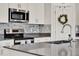 The kitchen has stainless steel appliances and a sink in the kitchen island with gray backsplash and countertops at 312 Inman Blvd, Winter Haven, FL 33881