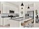 Bright kitchen features white cabinets, stainless steel appliances, a gray backsplash, and an island with seating at 312 Inman Blvd, Winter Haven, FL 33881