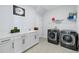 Laundry room with gray tile floors, modern washer and dryer, white cabinets, and sink at 3121 Buffington Pl, Oviedo, FL 32765